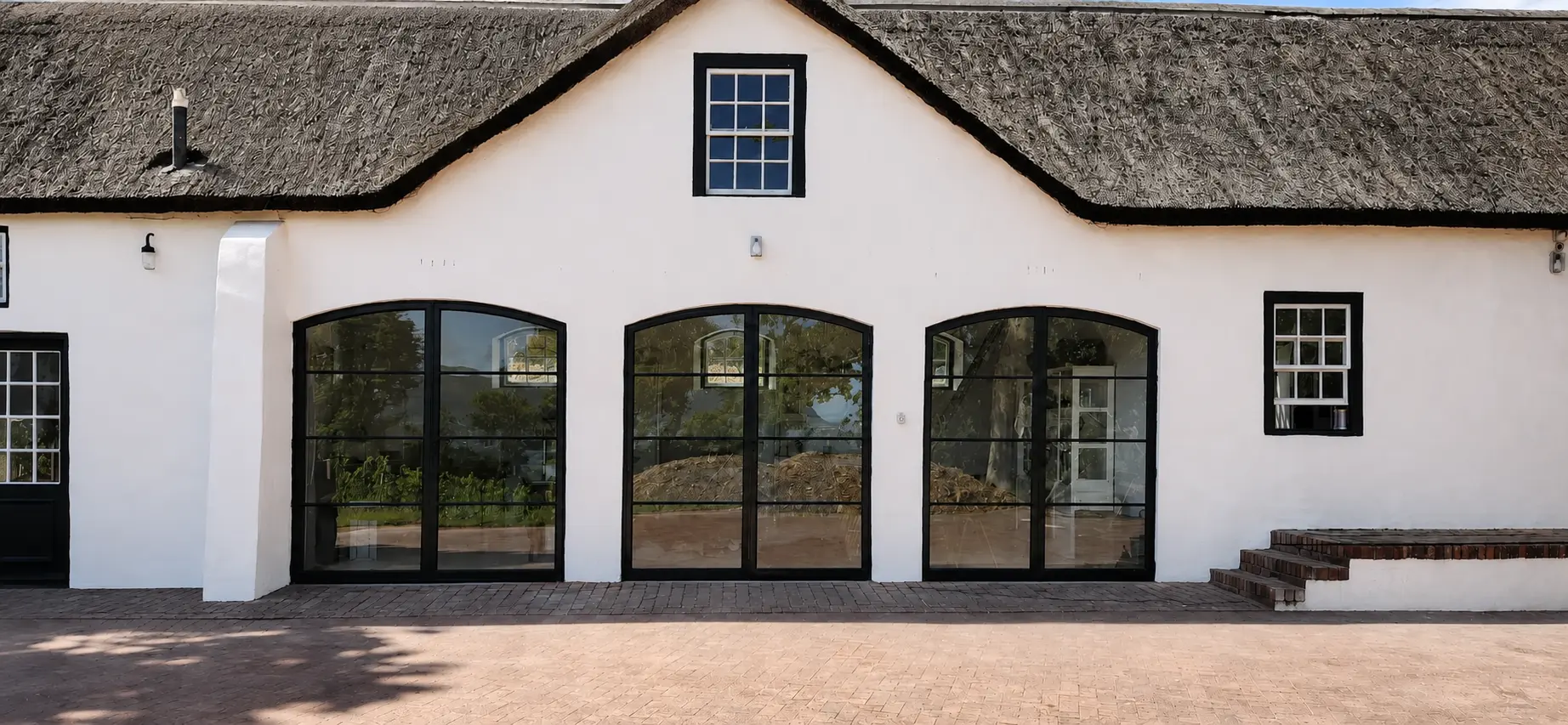 Straight-on view of three completed arched steel double-door sets at a Constantia cottage