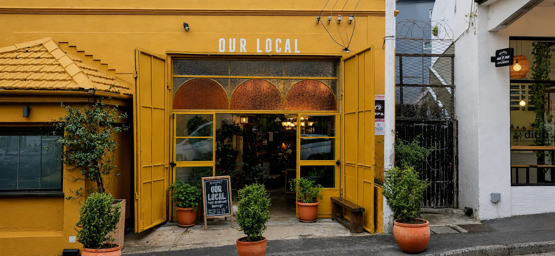 Squared front elevation of the completed yellow steel shopfront at Our Local